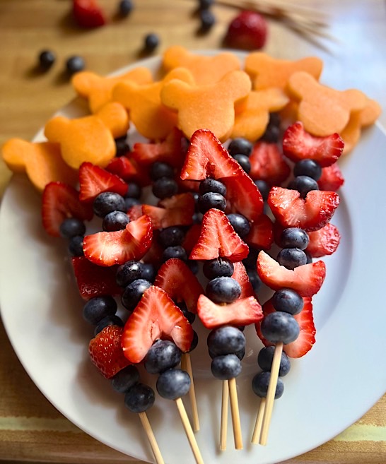 Disney-inspired fruit skewers with strawberries, blueberries, and Mickey Mouse shaped cantaloupe pieces.