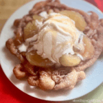 This indulgent Apple Pie funnel cake is a theme park-inspired treat that brings the magic home! Made with a quick Bisquick batter, it's fried to crispy perfection, sprinkled with powdered sugar, and loaded with dozy apple pie filling, creamy vanilla ice cream, and a caramel drizzle.