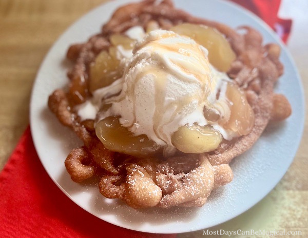 This indulgent Apple Pie funnel cake is a theme park-inspired treat that brings the magic home! Made with a quick Bisquick batter, it's fried to crispy perfection, sprinkled with powdered sugar, and loaded with dozy apple pie filling, creamy vanilla ice cream, and a caramel drizzle.