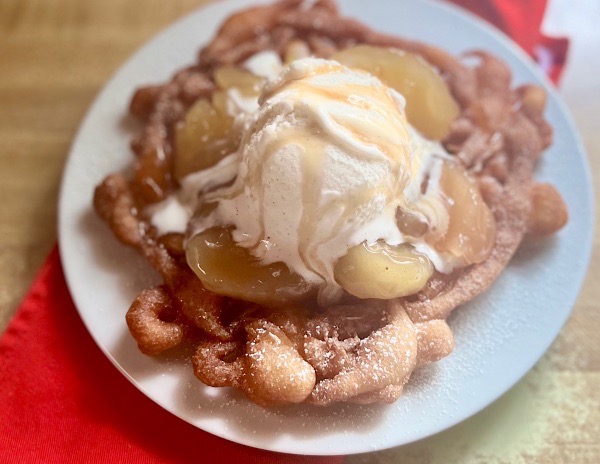 This indulgent Apple Pie funnel cake is a theme park-inspired treat that brings the magic home! Made with a quick Bisquick batter, it's fried to crispy perfection, sprinkled with powdered sugar, and loaded with dozy apple pie filling, creamy vanilla ice cream, and a caramel drizzle.