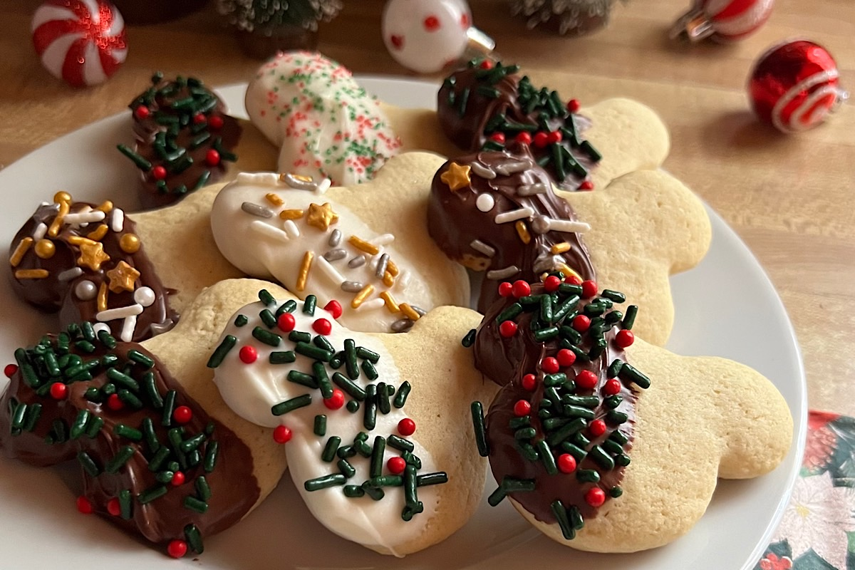 Mickey-shaped sugar cookies partially dipped in semi-sweet or white chocolate with red, green, silver, and gold sprinkles, arranged on a white plate for a cheerful Christmas in July treat.
