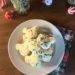 A plate of homemade Mickey-shaped Christmas Confetti Cookies with red & green sprinkles, set against a background of festive holiday decorations.
