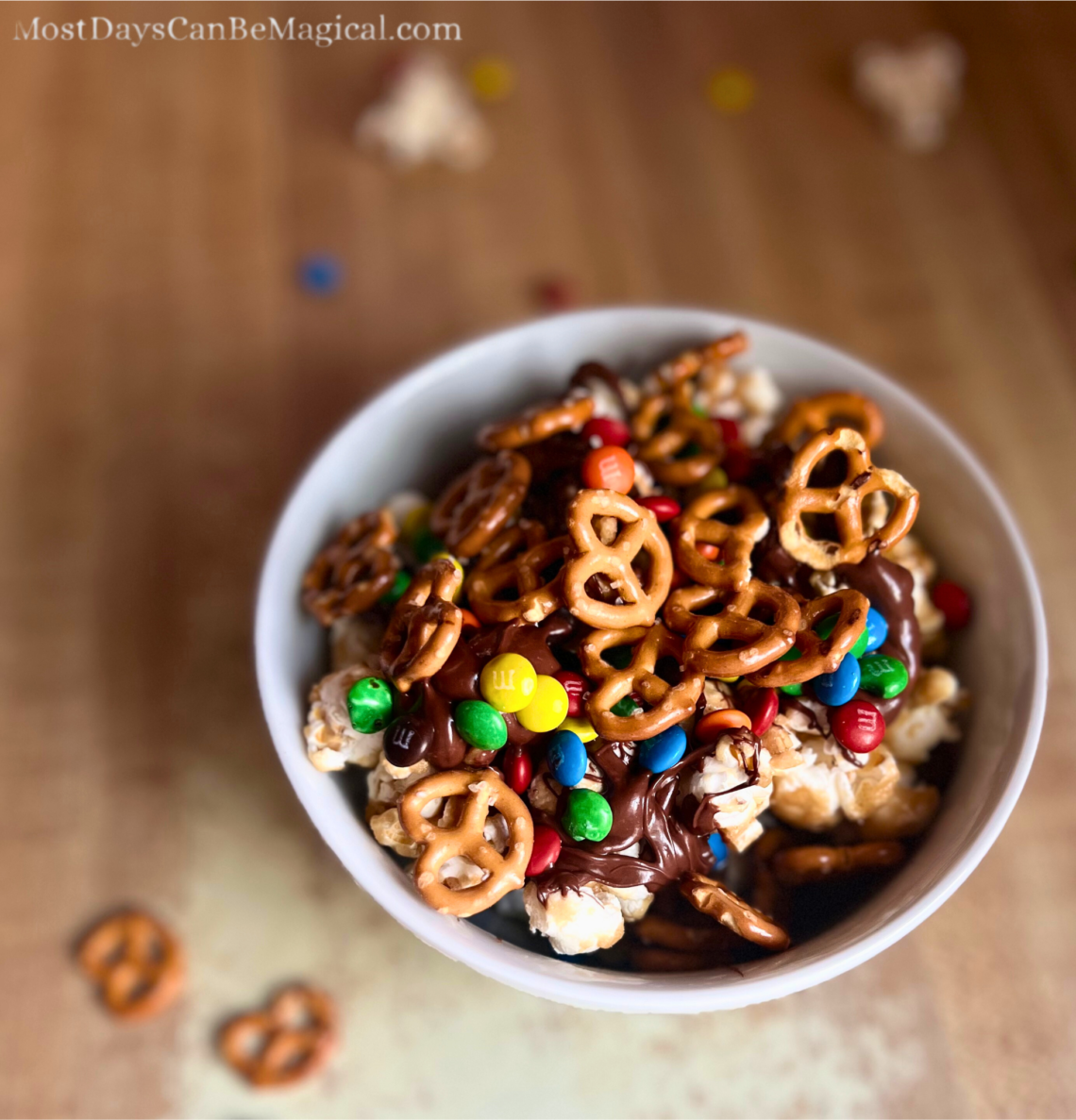 A Sweet and Salty Popcorn Bowl consisting of layers of caramel corn, chocolate drizzle, mimi M&Ms and mini pretzels.