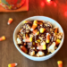 White bowl filled with caramel popcorn, chocolate drizzle, colorful candy corn, and a sprinkle of sea salt - a festive Disney-inspired Halloween movie night snack!
