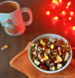 A white bowl filled with caramel corn layered with candy corn and chocolate drizzle. Inspired from the Main Street USA popcorn bowls.