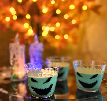 Oogie Boogie-inspired Pistachio Pudding Cups with an autumn lighted tree in the background setting the perfect Halloween scene.