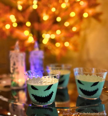 Oogie Boogie-inspired Pistachio Pudding Cups with an autumn lighted tree in the background setting the perfect Halloween scene.