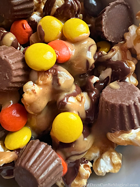 Disney-inspired peanut butter and chocolate caramel popcorn bowl topped with mini peanut butter cups and Reese's pieces.