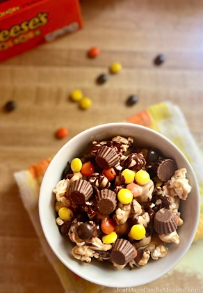 Disney-inspired peanut butter and chocolate caramel popcorn bowl topped with mini peanut butter cups and Reese's pieces.