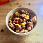 Disney-inspired peanut butter and chocolate caramel popcorn bowl topped with mini peanut butter cups and Reese's pieces.