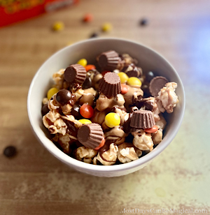 Disney-inspired peanut butter and chocolate caramel popcorn bowl topped with mini peanut butter cups and Reese's pieces.