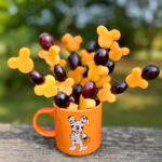 Cup of Disney-inspired Halloween Fruit skewers featuring Mickey-shaped cantaloupe and grapes.