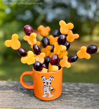 Cup of Disney-inspired Halloween Fruit skewers featuring Mickey-shaped cantaloupe and grapes.