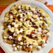 Overhead view of Disney-inspired Caramel apple nachos on a white plate topped with mini marshmallows, festive sprinkles, caramel, white chocolate, mini chocolate chips, and sea salt.