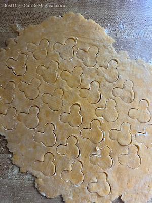 Rolled out cheddar cheese dough with Mickey shapes cut out of it.