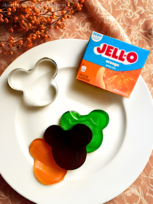 Plate with a box of orange gelatin mix, a Mickey-shaped cookie cutter and gelatin jigglers - a fun Disney-inspired Halloween finger food!