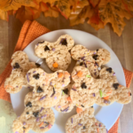 A plate of Disney-inspired Mickey-shaped Rice Krispies Treats with Halloween sprinkles and autumn leaves in the background.