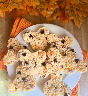 A plate of Disney-inspired Mickey-shaped Rice Krispies Treats with Halloween sprinkles and autumn leaves in the background.