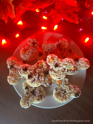 A plate of Disney-inspired Mickey-shaped Rice Krispies Treats with soft, spooky Halloween lighting and autumn leaves in the background.