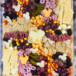 This adorable Halloween themed charcuterie board features Mickey-shaped meats and cheeses along with crackers, fruit, and candy corn.