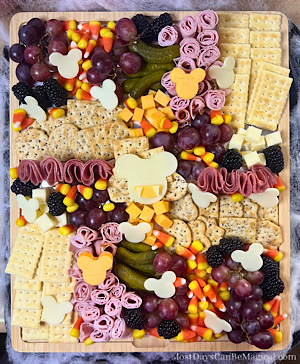 This adorable Halloween themed charcuterie board features Mickey-shaped meats and cheeses along with crackers, fruit, and candy corn.