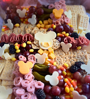 This adorable Halloween themed charcuterie board features Mickey-shaped meats and cheeses along with crackers, fruit, and candy corn.