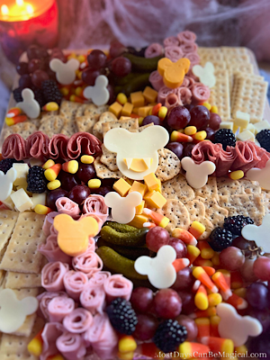 This adorable Halloween themed charcuterie board features Mickey-shaped meats and cheeses along with crackers, fruit, and candy corn.