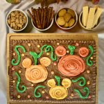 Buttercream board with Mickey-shaped pumpkins in different shades of orange in a chocolate buttercream pumpkin patch with assorted snacks for dipping.