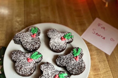 A white plate of Disney-inspired brownies with Mickey-shaped holly berries with leaves.