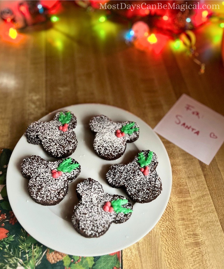 A white plate of Disney-inspired brownies with Mickey-shaped holly berries with leaves.