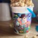 Homemade Sweet & Salty Maple Popcorn overflowing from the top of a popcorn bucket featuring Woody and other Toy Story characters.