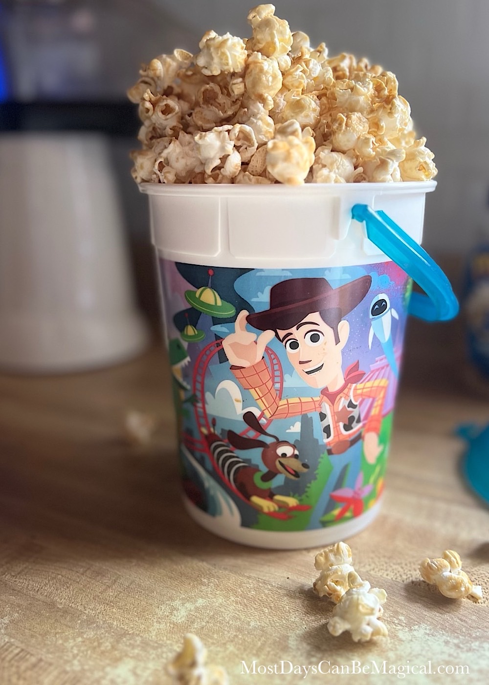 Homemade Sweet & Salty Maple Popcorn overflowing from the top of a popcorn bucket featuring Woody and other Toy Story characters.