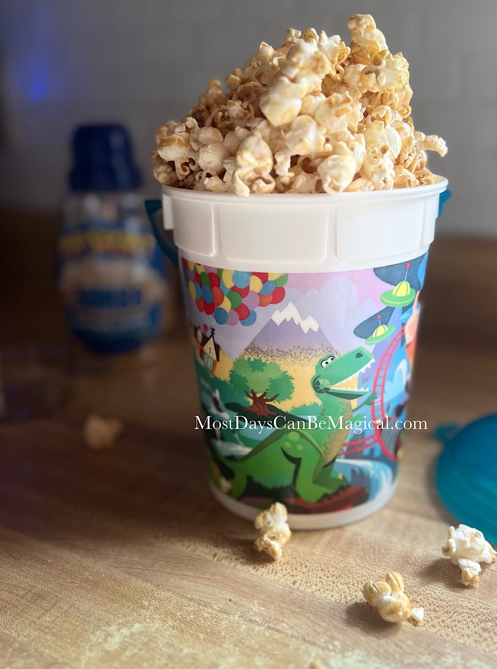 Homemade maple popcorn overflowing from a popcorn bucket featuring Rex from Toy Story.
